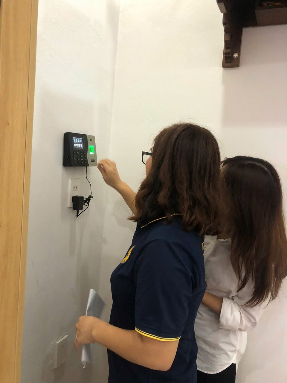 Nh&acirc;n vi&ecirc;n đăng k&yacute; v&acirc;n tay tr&ecirc;n m&aacute;y chấm c&ocirc;ng c&oacute; người hướng dẫn b&ecirc;n cạnh